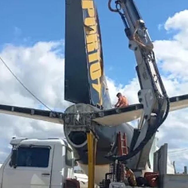 Caminhão munck retirando a cauda de um avião durante a desmontagem